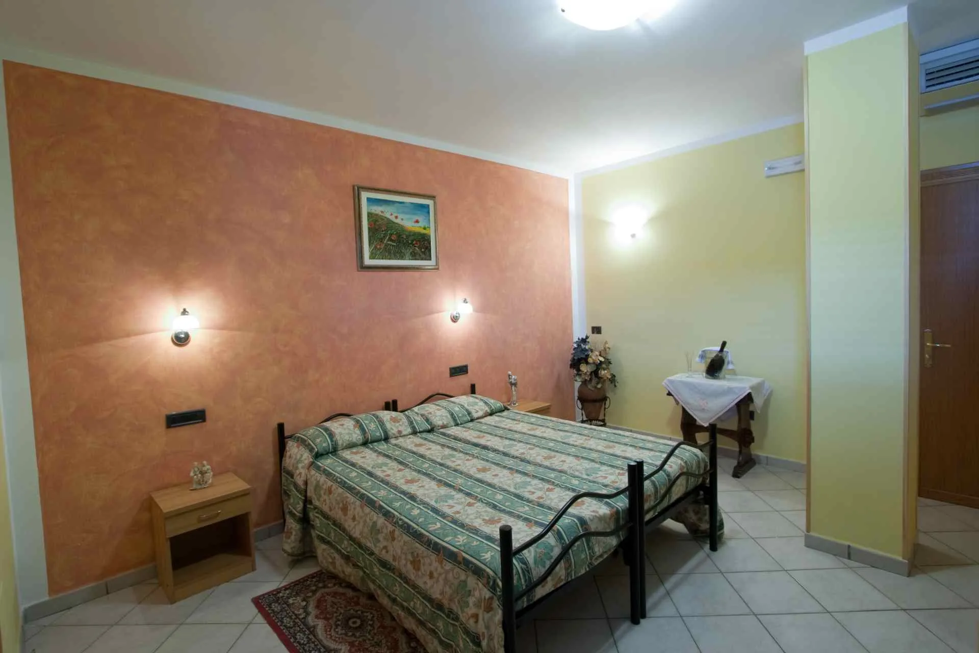 Dettaglio interno di una camera dell'Albergo Piandarca con comodini, lampade e biancheria curata