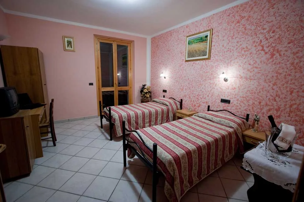 Camera matrimoniale rosa dell'Albergo Piandarca con letto a due piazze e pareti tinte in rosa tenue